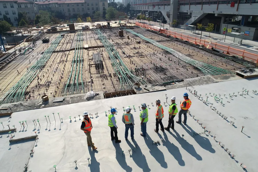 Geniş betonarme döşeme üzerinde yelekli ve baretli proje ekibi